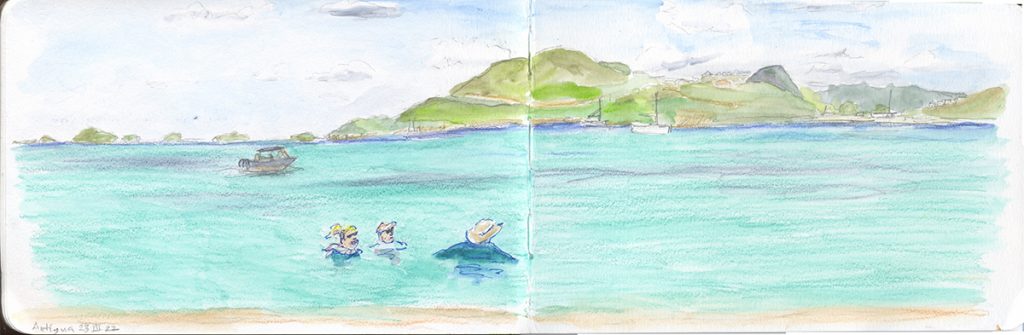 Panorama view of a beach in Antigua, with Mary and two friends in the water