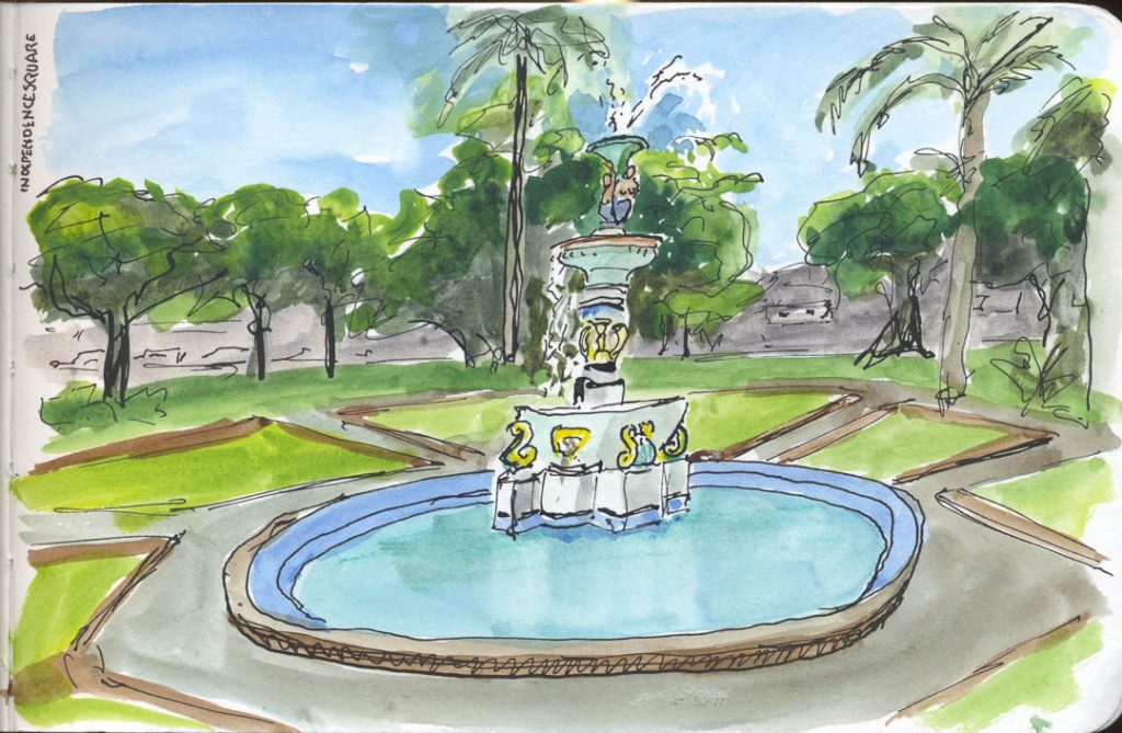 Ink and wash drawing of the colorful fountain in Independence Square, Bassaterre